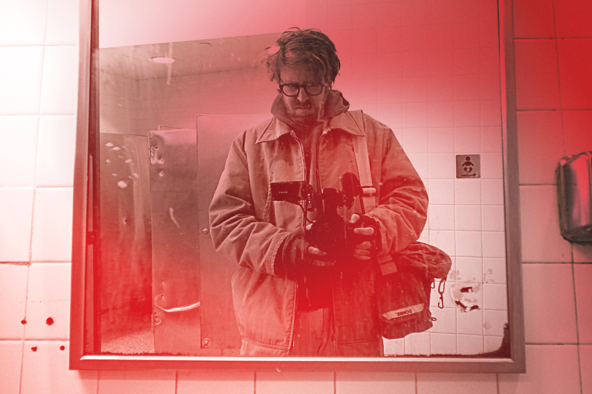 John Wilson records himself in a mirror holding a small video camera
